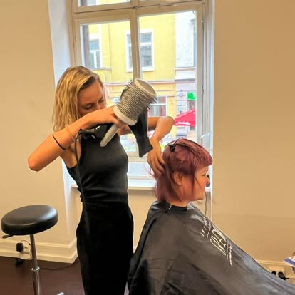 Friseurin föhnt die Haare einer Kundin