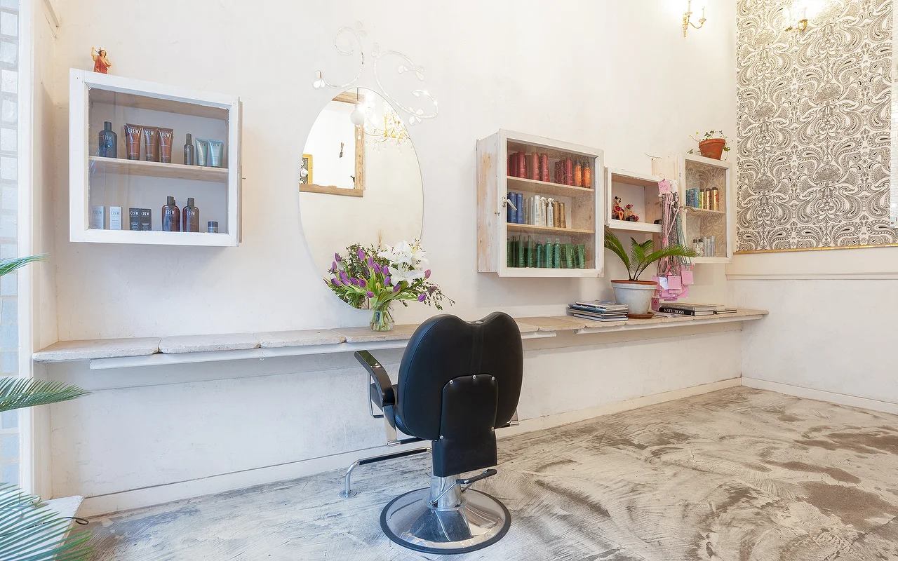 Innenraum des Salons mit Spiegel, Regalen und Frisierstuhl