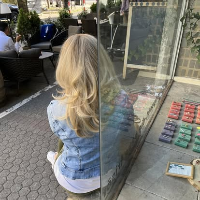 Kundin mit frisch gemachtem blondem Haar vor dem Salon