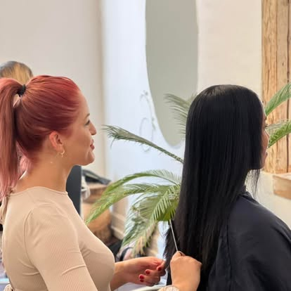 Friseurin prüft die Längen langer dunkler Haare